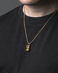Person wearing a black shirt with a gold necklace featuring a pendant.