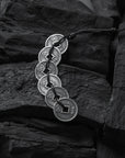 Silver coin bracelet on a dark stone surface