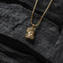 Gold necklace with a pendant on a dark stone surface