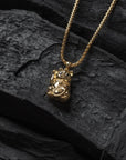 Gold necklace with a pendant on a dark stone surface