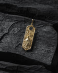 Gold turtle pendant with intricate design on a dark stone surface