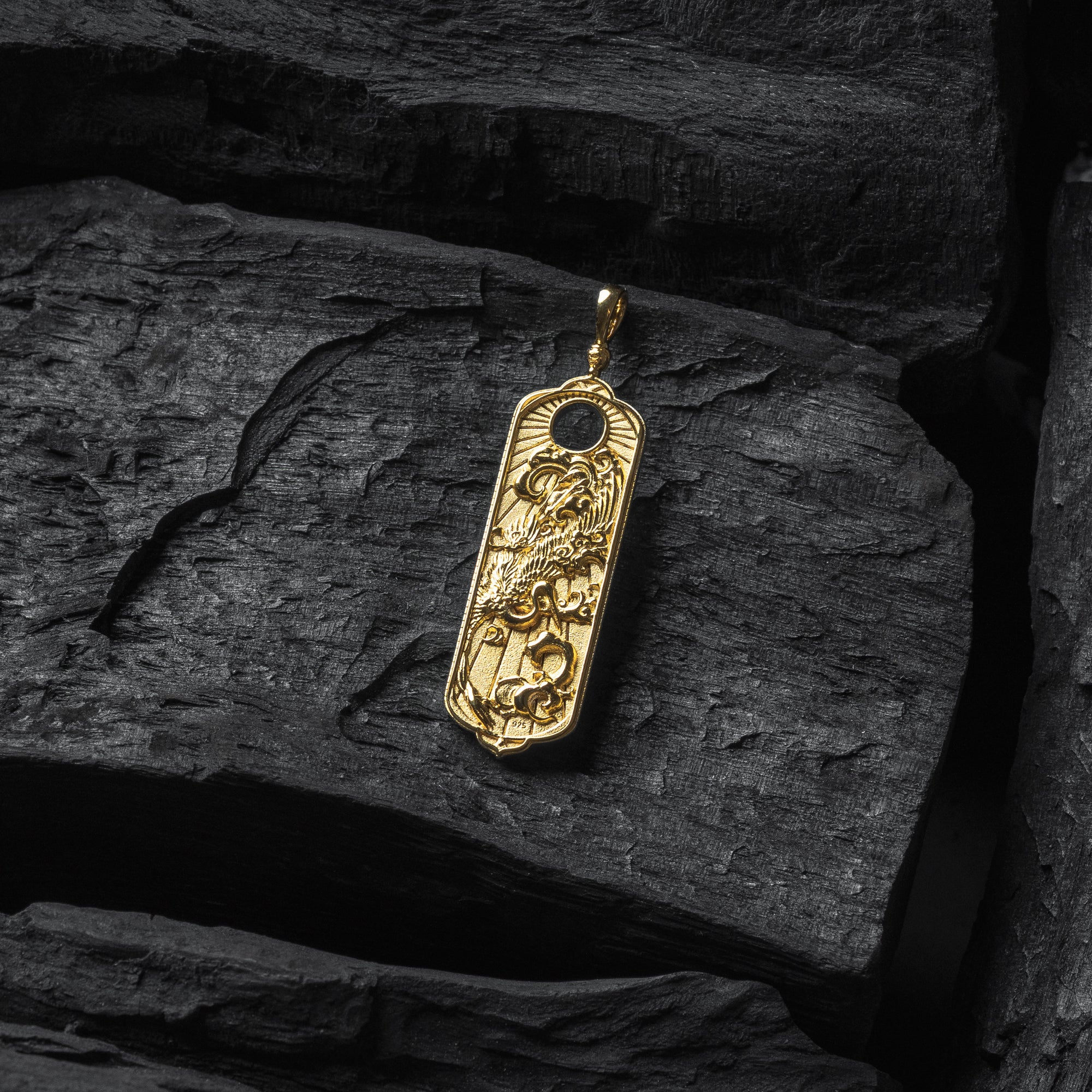 Gold crane pendant with intricate design on a dark stone surface