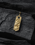 Gold crane pendant with intricate design on a dark stone surface