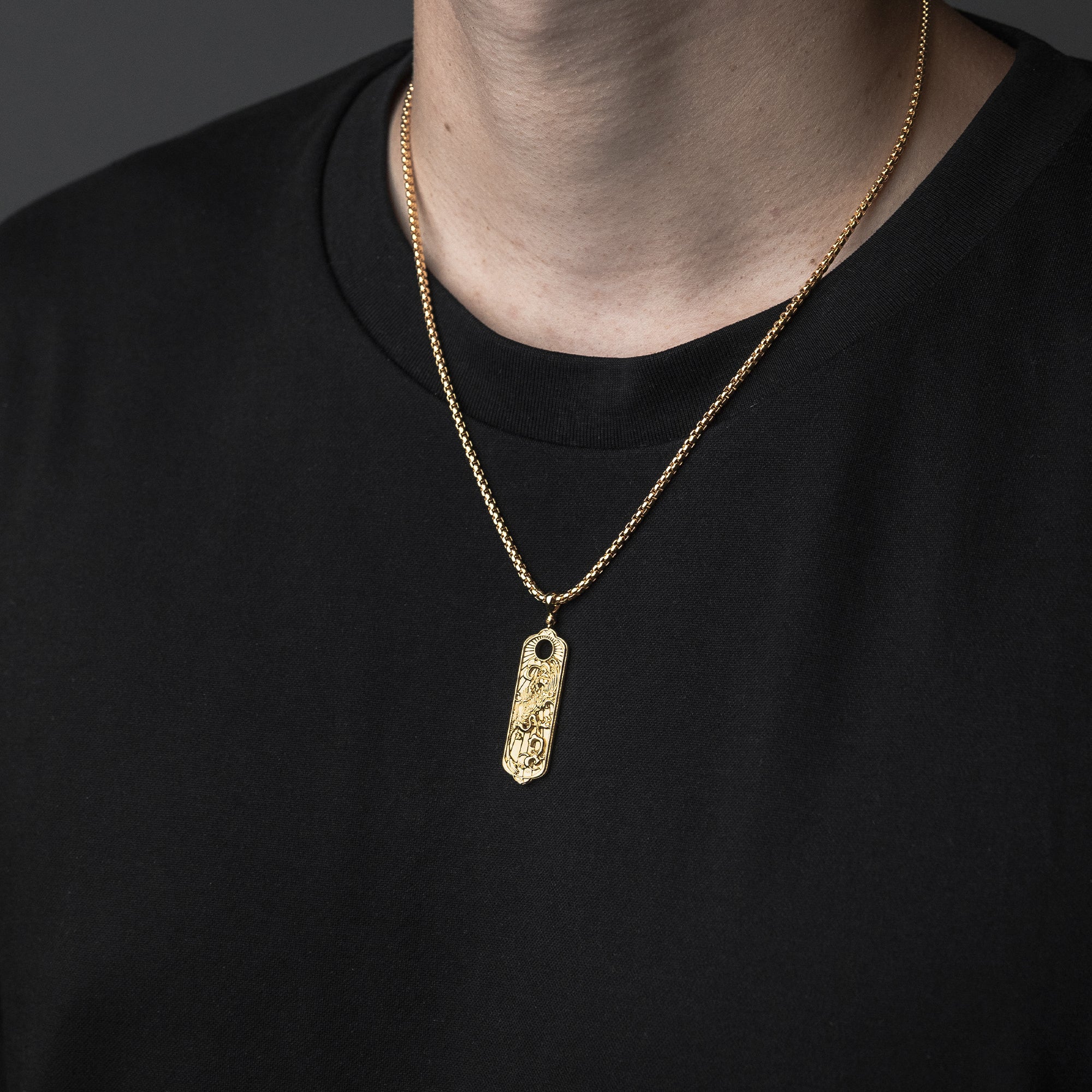Gold necklace with a pendant on a black background