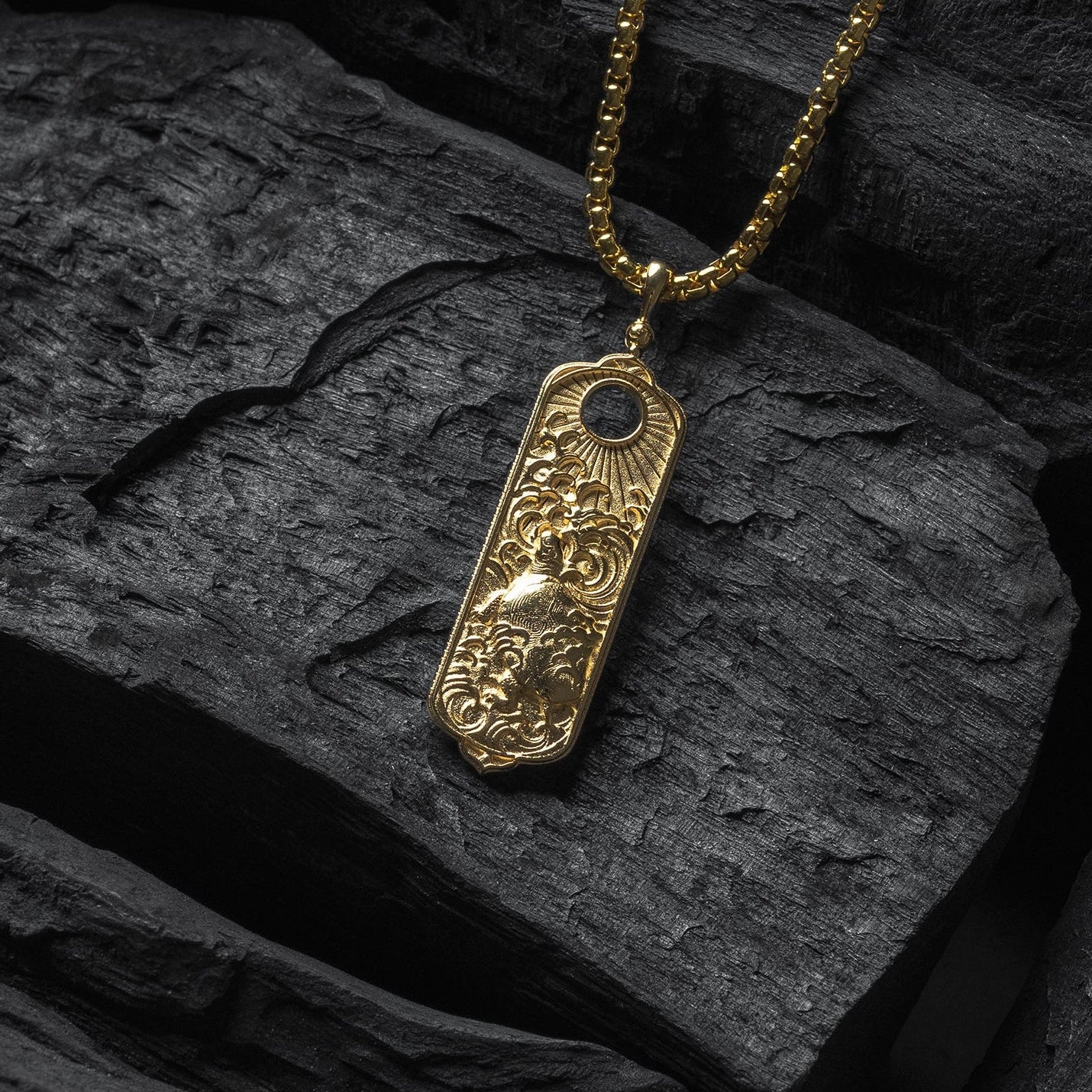Gold necklace with a detailed pendant on a dark stone surface