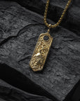 Gold necklace with a detailed pendant on a dark stone surface