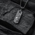 Silver necklace with a pendant on a dark stone surface